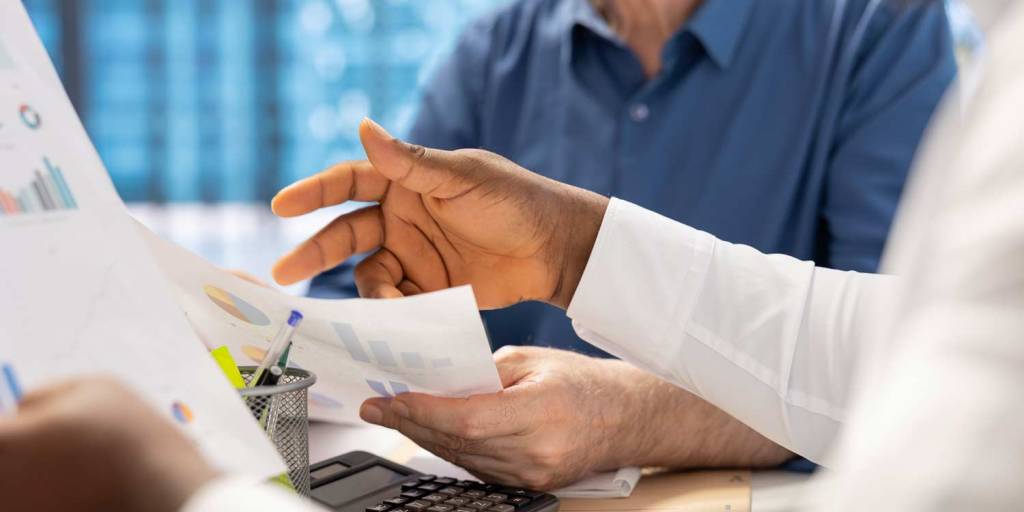 Dois homens com contrato na mão conversando sobre a crise nas comercializadoras de energia