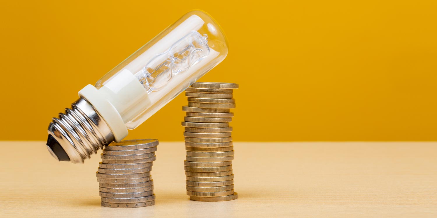 montanha de moedas com uma lâmpada em cima, mostrando o peso do reajuste da conta de luz em 2026